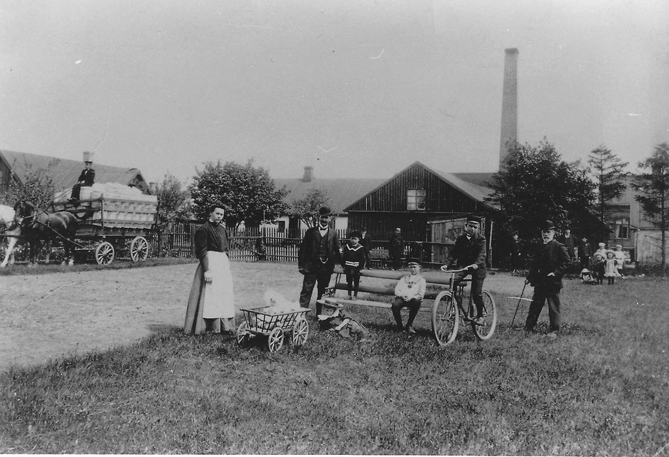 En bild på familjen som drev tunnbinderiet, uppställda framför sin verksamhet i kläder från början på 1900-talet