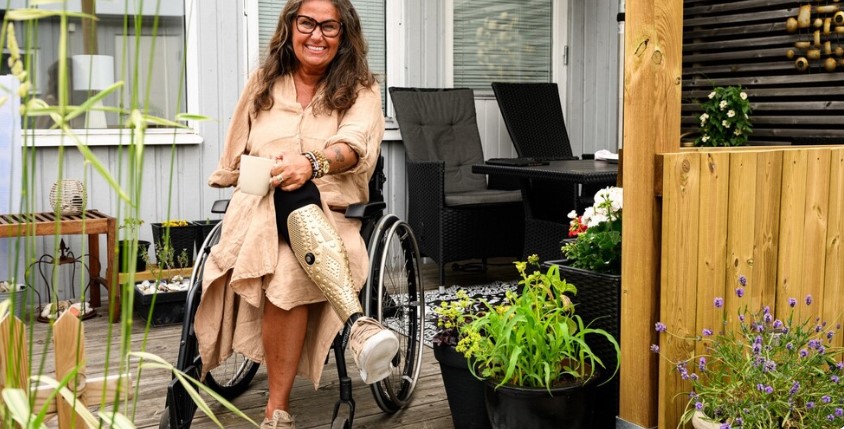 Gittel Ullebo sitter i rullstol på uteplats, ser glad ut. Föreläsning i Sjöbo om psykisk ohälsa.