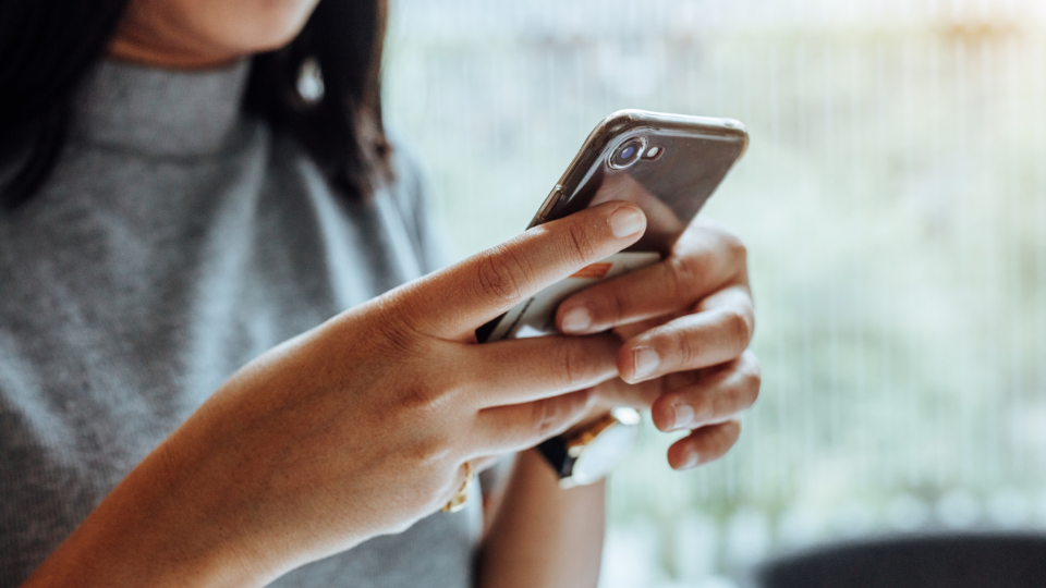 En kvinnas händer håller i en mobiltelefon
