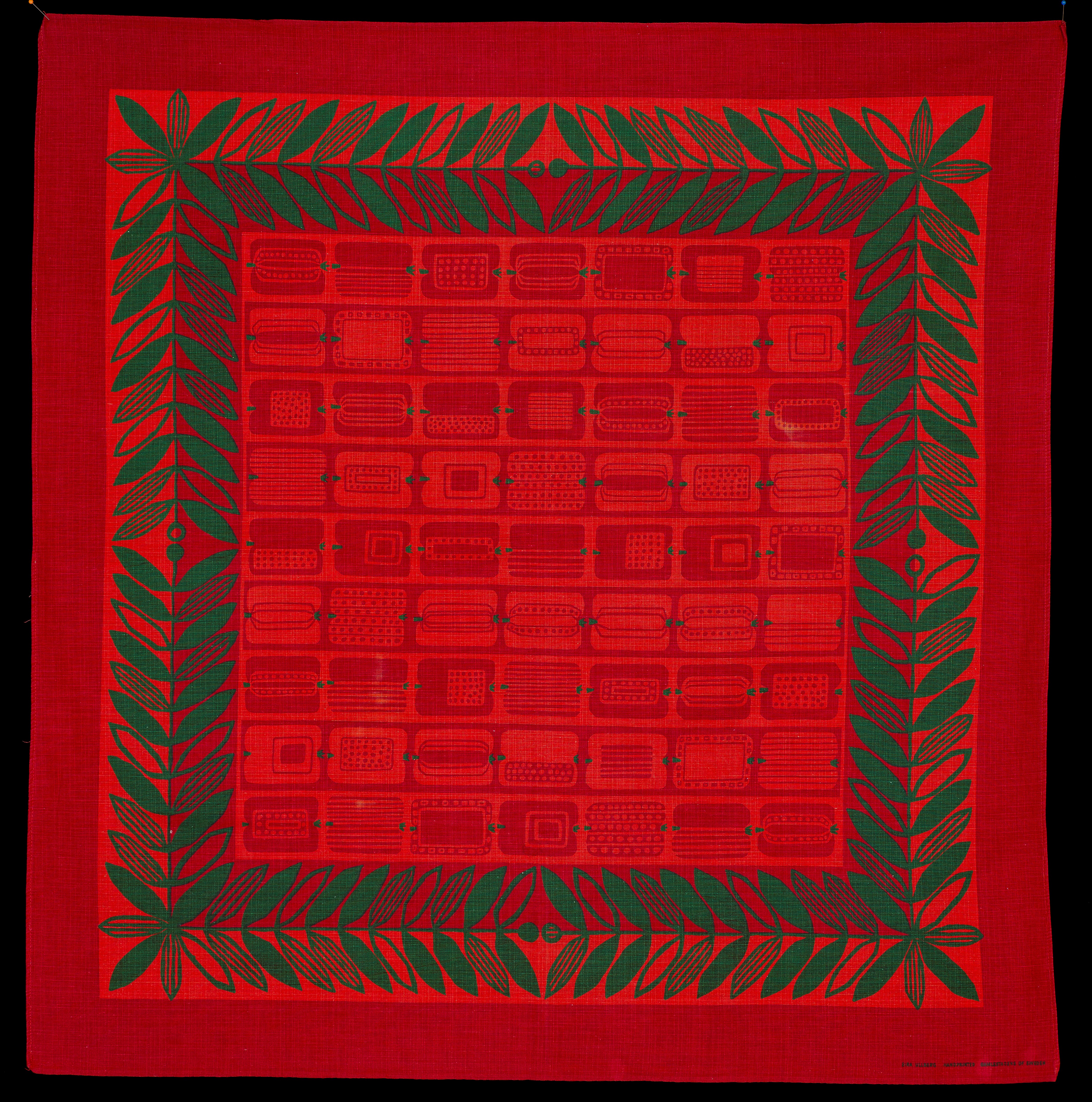 En röd julduk med gröna blad och geometriska, fruktliknande mönster på