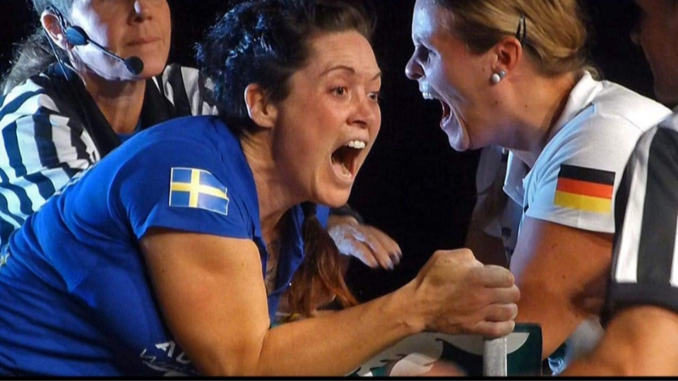 Två kvinnor med landslagskläder (Sverige/Tyskland) mitt i en armbrytningsmatch