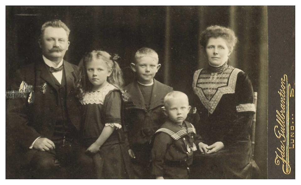 Foto på en familj; en kvinna, en man, tre barn, fotograferade i början av 1900-talet av Ida Gullbrandtson. 