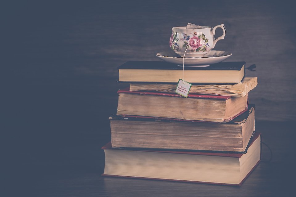 En trave böcker med en kopp te på toppen